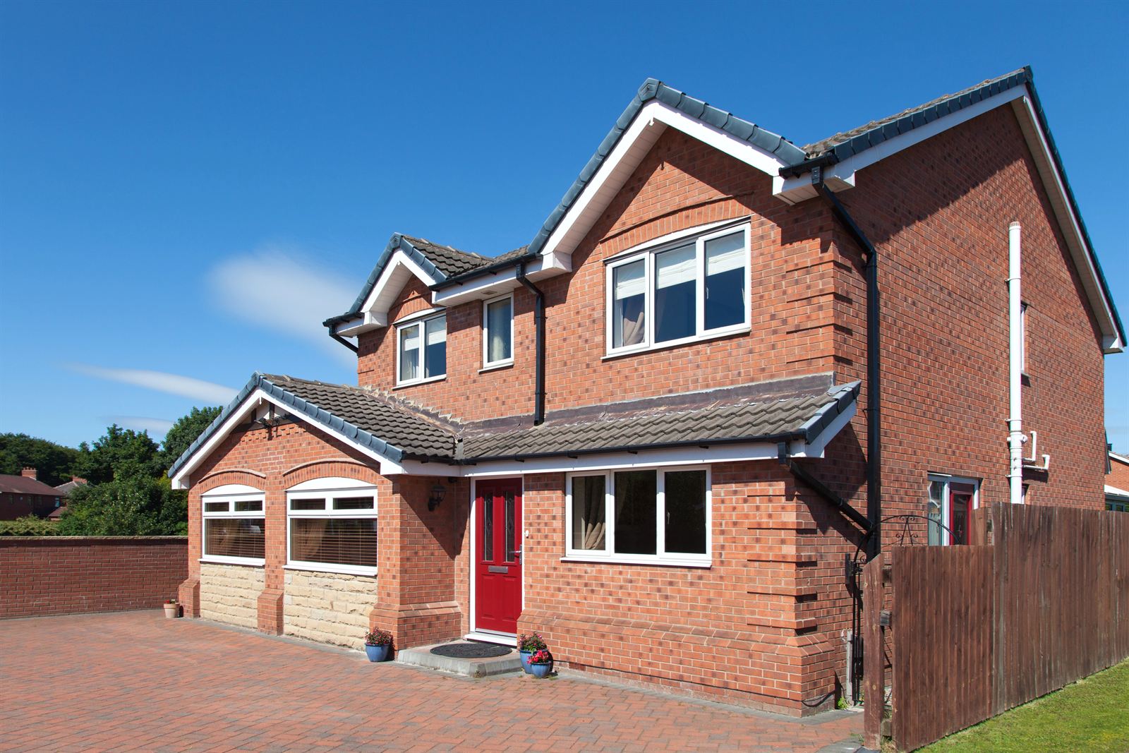 A well-kept detached brick house with a red front door